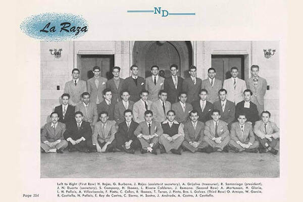 A black and white photo of the La Raza student organization at the University of Notre Dame. Thirty-one men in suits pose for a group photo in front of a building entrance. Three rows of students are seated on the ground, while two rows stand behind them. The title "La Raza" and "ND" are printed above the photo, and a caption below lists the names and positions of each member.